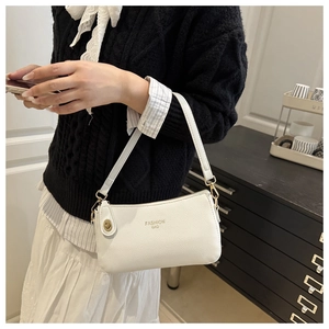 Detail of white lychee texture shoulder bag with gold FASHION BAG print and metal clasp