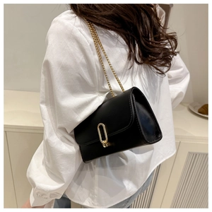 Détail d'un sac bandoulière en cuir noir avec boucle dorée et bandoulière en chaîne