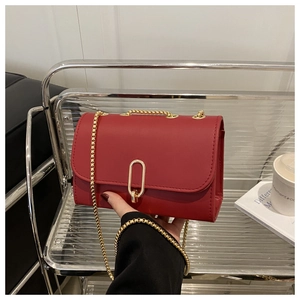 Détail du sac rouge en cuir mat à chaîne avec boucle dorée dans un décor lifestyle