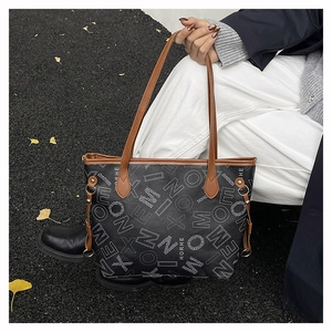 Détail d'un cabas imprimé avec poignées en cuir marron et rivets en extérieur