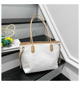 Detail of white plush tote bag showing soft sherpa texture and brown leather trim accents