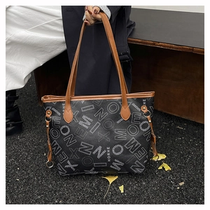 Détail du grand sac cabas noir avec imprimé lettres blanches et poignées en cuir marron