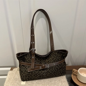 Retro leopard print tote bag with brown leather straps on a soft beige blanket