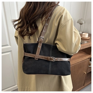 Detail of a large canvas shoulder bag with leather straps on a model in a warm setting