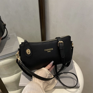 Retro black leather shoulder bag with gold hardware and logo on a stylish grey book