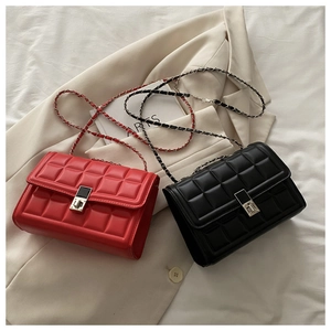 Detail showing red and black square quilted chain bags with metal buckles on fabric
