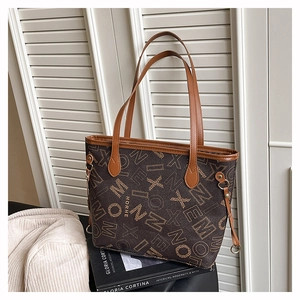 Détail d'un grand sac cabas marron à imprimé lettrage contre des volets blancs