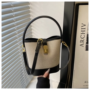 Detail of canvas bucket bag with black leather trim and elegant gold metal buckle