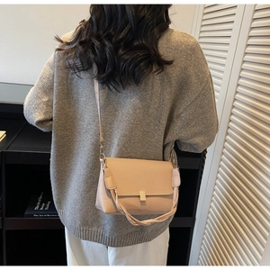 Detail of nude leather crossbody bag with golden metal buckle and woven handle detail