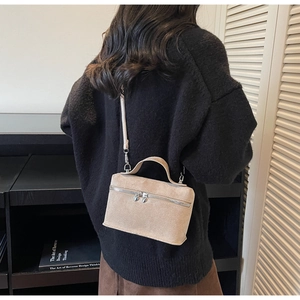 Vue arrière du modèle portant un sac bandoulière en daim beige avec détails zippés
