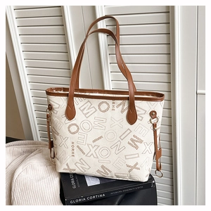 Détail du sac cabas en toile avec anses en cuir marron et imprimés de lettres d'art