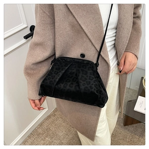 Détail du sac bandoulière froncé à imprimé léopard noir porté avec un manteau d'hiver