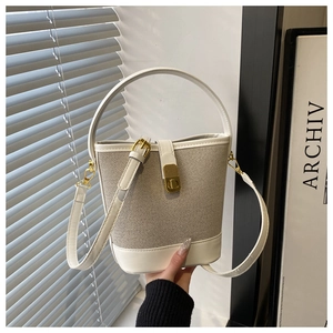 Detail of minimalist bucket bag featuring white faux leather and beige canvas stitching