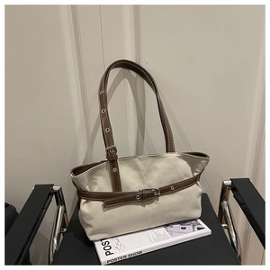 Dettaglio della borsa tote in tela beige con cinturini in pelle marrone e fibbia