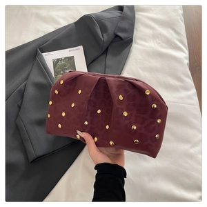 Close-up of burgundy pleated cloud clutch with leopard print and gold metal studs