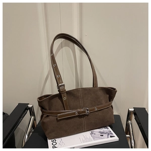 Dettaglio borsa tote in pelle scamosciata marrone con cuciture bianche e fibbie argento