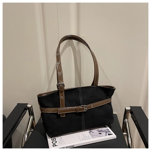 Dettaglio di una borsa tote in tela nera con cinturini in pelle marrone e fibbia d'argento