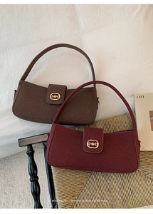 Close-up of vintage suede underarm bags with metal horsebit hardware on a woven chair
