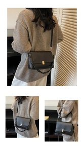 Detail of black leather baguette bag featuring golden buckle and woven shoulder strap