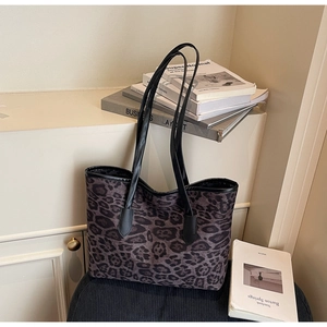 Detail view of large leopard print tote bag with black faux leather handles and pattern
