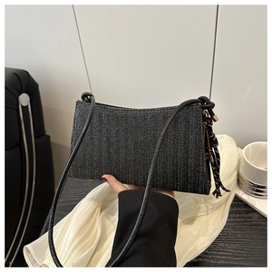 Detail of black woven shoulder bag showing fine V-shape texture and slim strap