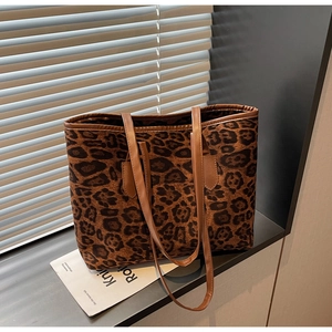Detail of leopard print tote bag featuring brown leather straps and large capacity