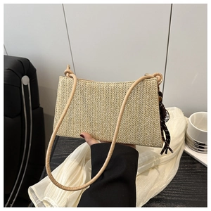Close-up of beige woven shoulder bag featuring fine herringbone texture and leather strap