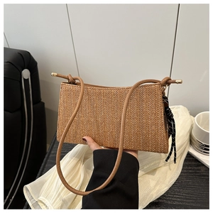 Detail of a brown woven straw tote bag featuring long leather straps and a polka dot scarf