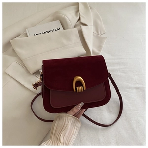 Close-up of deep wine red crossbody bag with golden U-shaped lock and suede leather detail