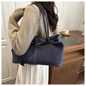 Detail of vintage denim tote bag with contrast stitching and leather handles on a model