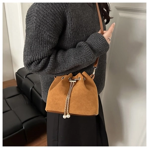 Detail of brown suede bucket bag with gold chain drawstring and pearl pendants decor