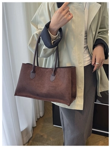 Detailed close-up of dark brown suede tote bag carried by model in light trench coat