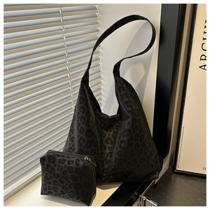 Detailed view of leopard print tote bag with matching zipper pouch on artistic backdrop