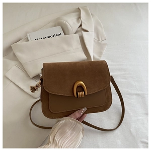 Detail of vintage brown shoulder bag showing suede flap and gold U-shaped hardware
