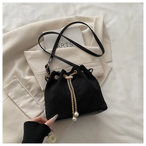 Detail of black suede bucket bag with gold chain drawstring and elegant pearl charms