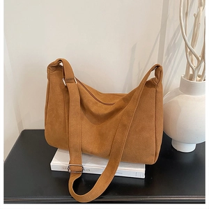 Détail du sac hobo en daim marron chaud avec sangle réglable et boucles métalliques