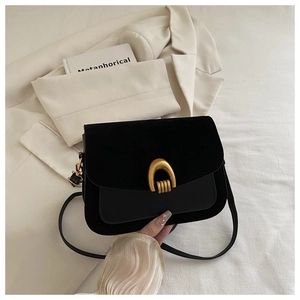 Detail of black leather flap bag featuring textured paneling and a gold U-shaped metal buckle