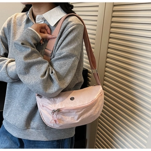 Detailed view of pink nylon crossbody bag with dual zippers and adjustable wide strap