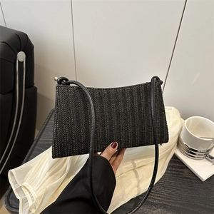 Chic black woven tote bag with V-shaped texture and slim strap in a stylish setting