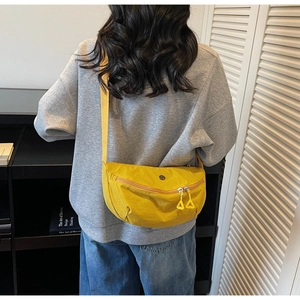 Back view of model wearing a bright yellow nylon crescent crossbody bag with adjustable strap