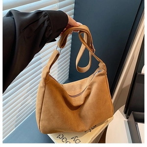 Détail d'un sac hobo en daim marron avec fermeture éclair et bandoulière réglable