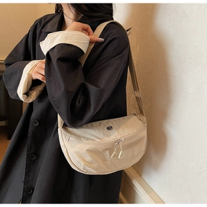 Detail of beige crescent nylon bag with adjustable strap and metallic triangle zipper pull