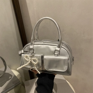 Silver metallic Boston handbag with twin handles, pearl bow charm and flap pockets