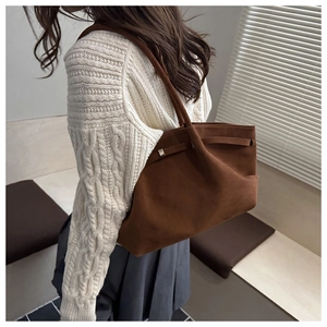Detail of dark brown matte tote bag with decorative strap and metallic buckle accents
