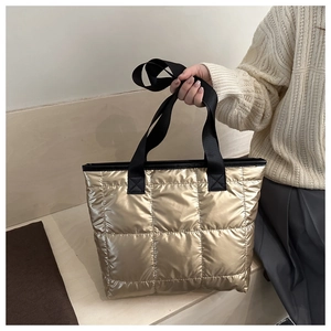Detail of quilted metallic tote bag with gold fabric and black strap handles
