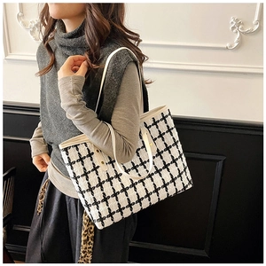 Detalle del bolso tote de tweed blanco y negro con asas de cuero y diseño espacioso