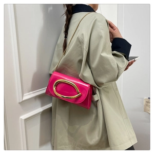 Pink patent leather shoulder bag with gold metal buckle shown on a model