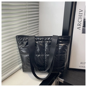 Detail shot of the black quilted puffer tote bag on a window sill showing the nylon straps