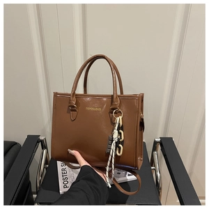 Close-up of brown PU leather tote with metal chain and chocolate charm detail