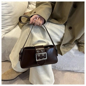Détail du sac à bandoulière en cuir marron foncé avec une grande boucle en métal argenté